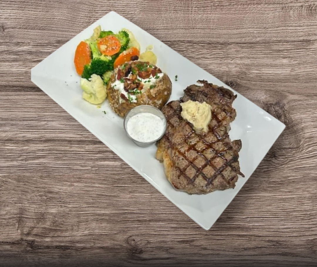 16 oz ribeye with vegetables and a baked potato